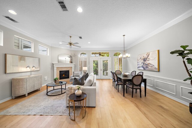 living room featuring a fireplace, visible vents, light wood finished floors, and ornamental molding