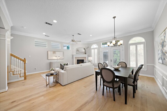 dining area with recessed lighting, a warm lit fireplace, light wood-style floors, and crown molding