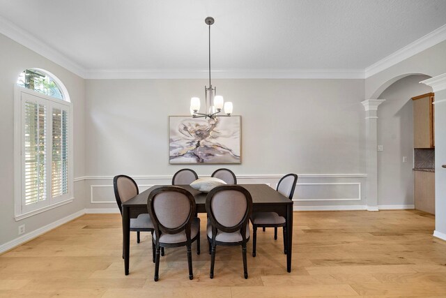 dining area with arched walkways, light wood-type flooring, a chandelier, ornate columns, and crown molding