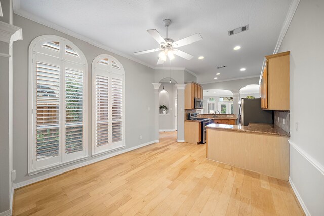 kitchen featuring light wood finished floors, visible vents, a ceiling fan, decorative columns, and appliances with stainless steel finishes