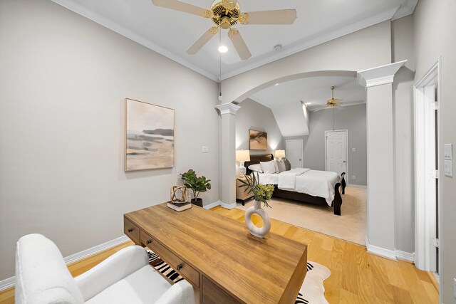 bedroom featuring baseboards, arched walkways, light wood finished floors, and decorative columns