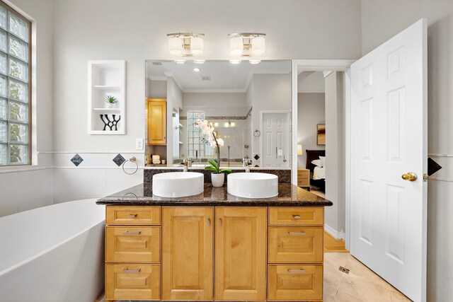 full bath featuring double vanity, a healthy amount of sunlight, crown molding, and a sink