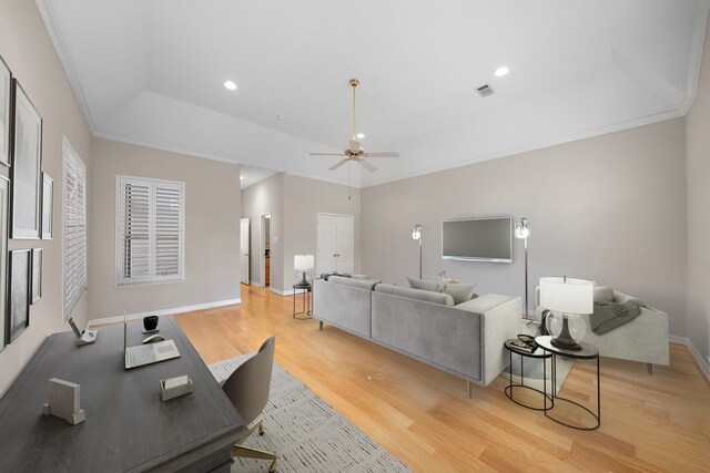 office space with a ceiling fan, light wood-style floors, a raised ceiling, baseboards, and ornamental molding