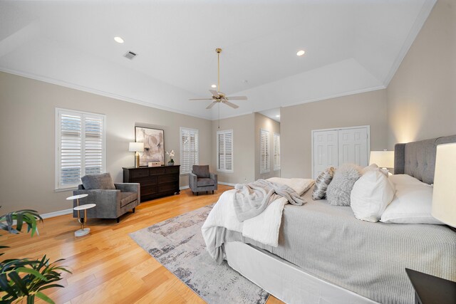 bedroom with a tray ceiling, visible vents, ornamental molding, light wood-style floors, and baseboards