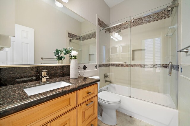 bathroom featuring combined bath / shower with glass door, vanity, tile patterned floors, and toilet