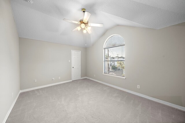 carpeted empty room with lofted ceiling, a ceiling fan, and baseboards