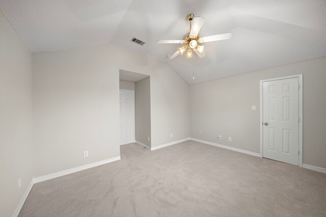 empty room with ceiling fan, light carpet, baseboards, lofted ceiling, and visible vents