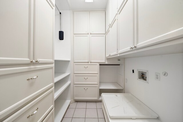 laundry room featuring electric dryer hookup, cabinet space, light tile patterned flooring, and washer hookup