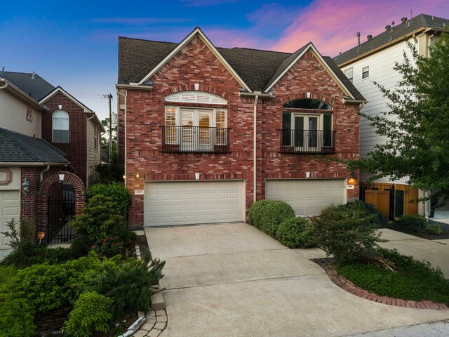 view of front facade with brick siding, french doors, driveway, and a garage