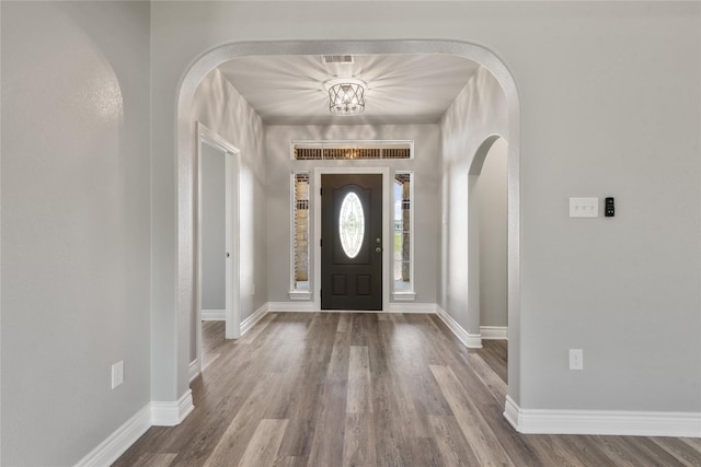 entryway with a chandelier, visible vents, baseboards, and wood finished floors