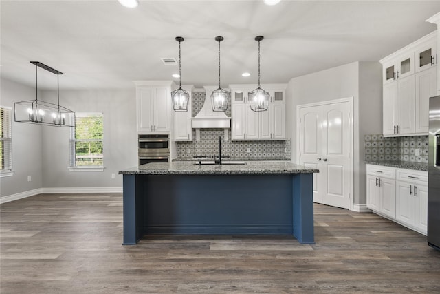 kitchen featuring white cabinetry, visible vents, dark stone countertops, baseboards, and backsplash