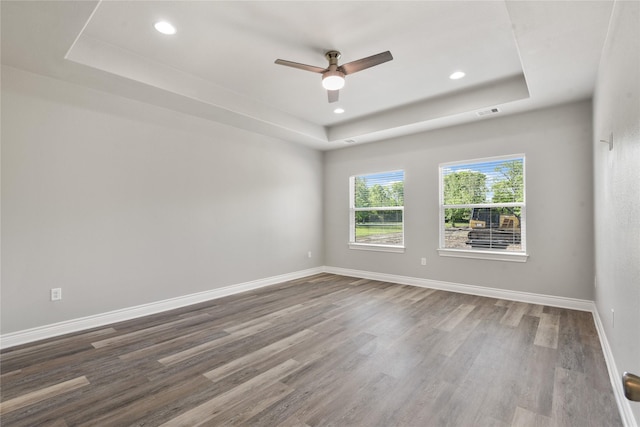 empty room featuring baseboards, a raised ceiling, a ceiling fan, recessed lighting, and wood finished floors