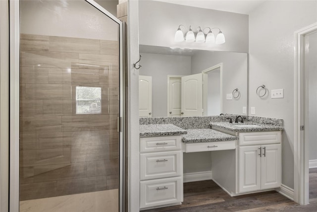 bathroom featuring a shower stall, vanity, baseboards, and wood finished floors