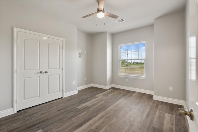 empty room with visible vents, ceiling fan, baseboards, and dark wood-style floors