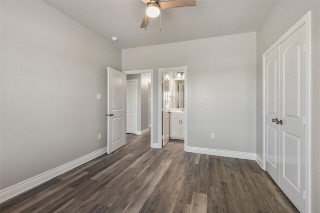 unfurnished bedroom with ceiling fan, ensuite bathroom, baseboards, and dark wood finished floors