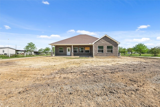 back of house featuring brick siding and covered porch
