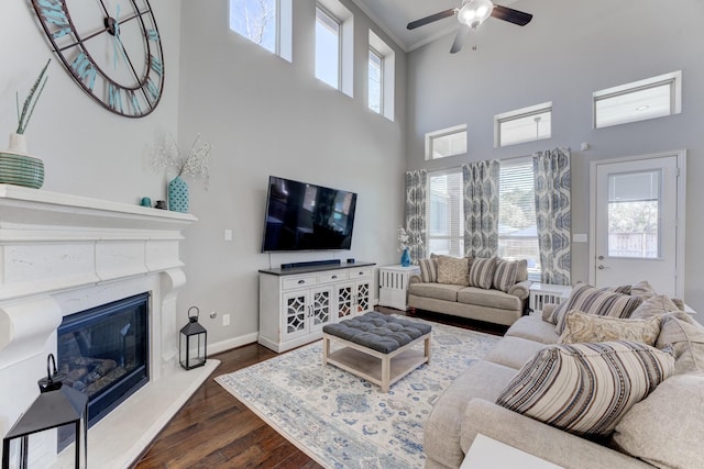 living room featuring ceiling fan, a wealth of natural light, a towering ceiling, and dark wood finished floors