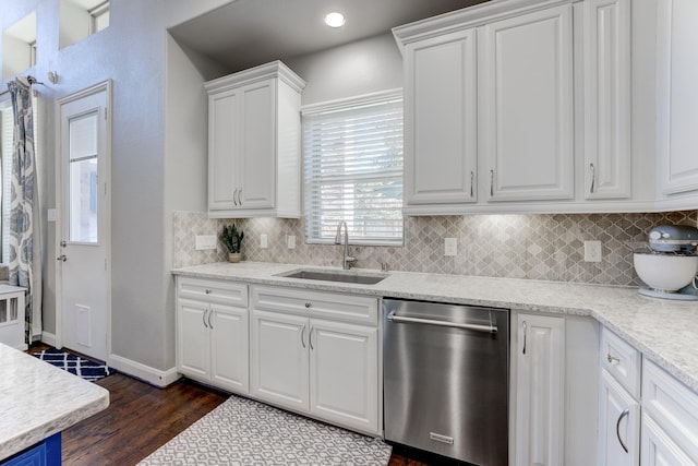 kitchen with tasteful backsplash, white cabinets, a sink, dark wood-type flooring, and stainless steel dishwasher
