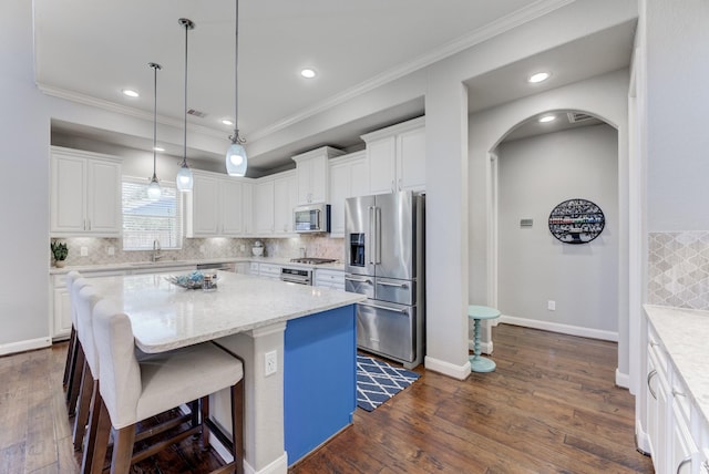 kitchen with stainless steel appliances, arched walkways, ornamental molding, and backsplash