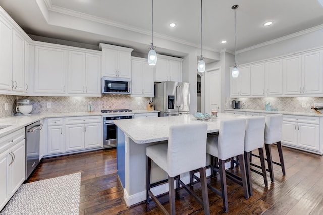 kitchen featuring dark wood-style flooring, backsplash, a kitchen island, a kitchen bar, and stainless steel appliances