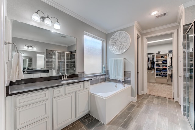 bathroom with visible vents, a spacious closet, crown molding, a stall shower, and a garden tub