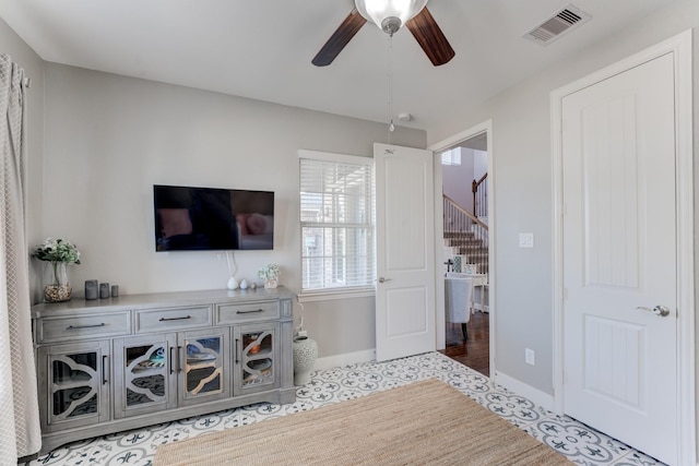 living room featuring ceiling fan, baseboards, visible vents, and stairway