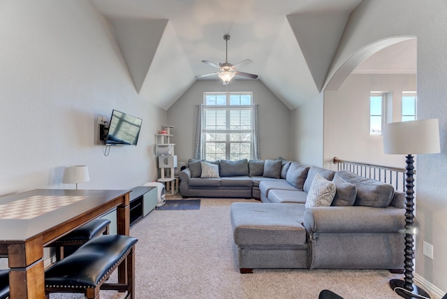carpeted living area with arched walkways, a ceiling fan, and vaulted ceiling