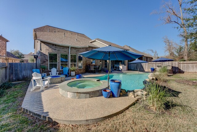 view of pool with a patio area, a pool with connected hot tub, a fenced backyard, and an outdoor fire pit