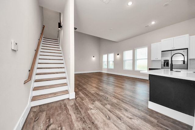 interior space featuring light countertops, wood finished floors, baseboards, stainless steel refrigerator with ice dispenser, and white cabinetry