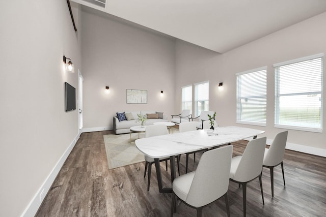 dining room with a high ceiling, baseboards, and dark wood-style floors