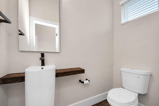 half bath with baseboards and toilet