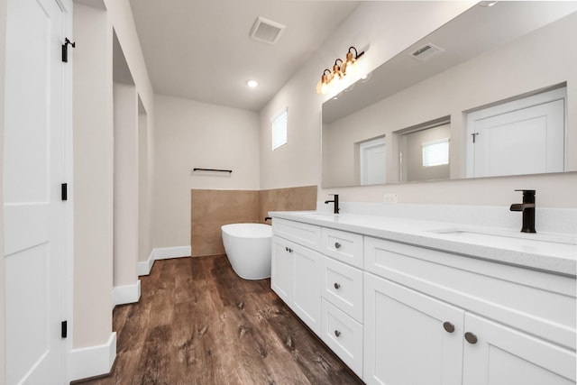 bathroom with a freestanding tub, double vanity, visible vents, and a sink