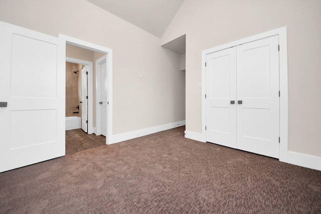 unfurnished bedroom featuring lofted ceiling, a closet, baseboards, and carpet floors