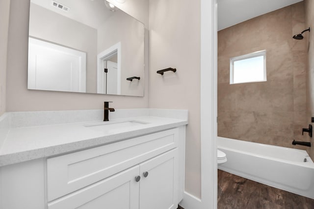 bathroom with toilet, visible vents, shower / bath combination, wood finished floors, and vanity