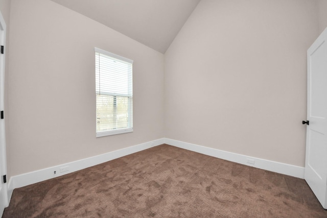 carpeted spare room with vaulted ceiling and baseboards