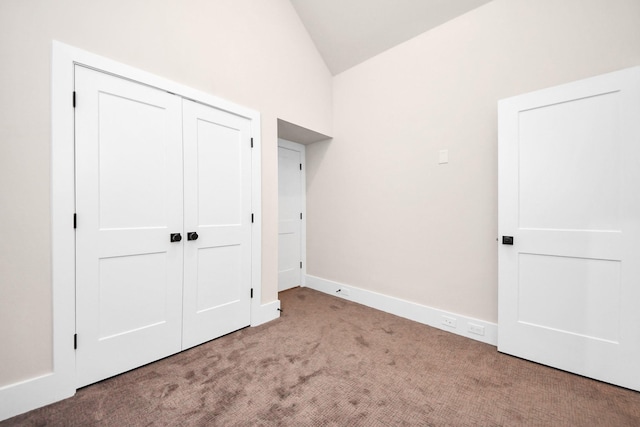 unfurnished bedroom with baseboards, vaulted ceiling, carpet flooring, and a closet