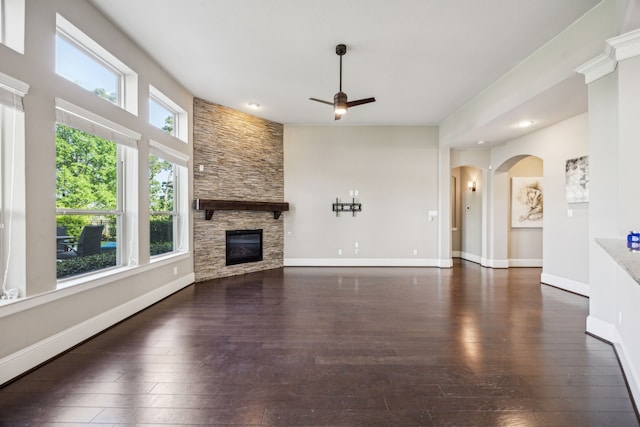 8227 Caroline Ridge Dr, Humble, TX 77396 - unfurnished living room featuring a ceiling fan, hardwood / wood-style floors, a fireplace, arched walkways, and baseboards