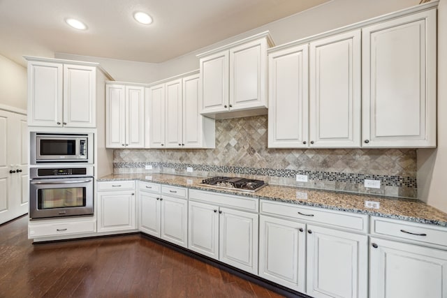 8227 Caroline Ridge Dr, Humble, TX 77396 - kitchen with appliances with stainless steel finishes, decorative backsplash, light stone counters, white cabinets, and recessed lighting