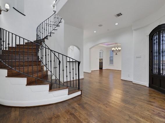 1408 W 23rd St, Houston, TX 77008 - entrance foyer featuring visible vents, arched walkways, an inviting chandelier, stairway, and wood finished floors