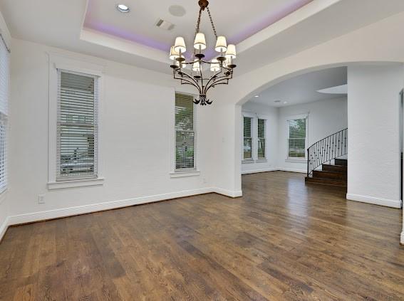 1408 W 23rd St, Houston, TX 77008 - unfurnished dining area with a tray ceiling, wood finished floors, an inviting chandelier, and baseboards