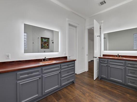 1408 W 23rd St, Houston, TX 77008 - bathroom with two vanities, visible vents, a sink, and wood finished floors