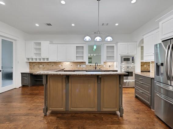 1408 W 23rd St, Houston, TX 77008 - kitchen with appliances with stainless steel finishes, decorative backsplash, open shelves, and white cabinets