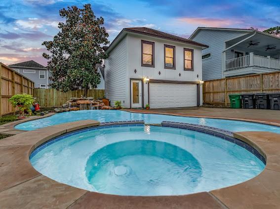 1408 W 23rd St, Houston, TX 77008 - pool at dusk featuring fence, a pool with connected hot tub, and a ceiling fan