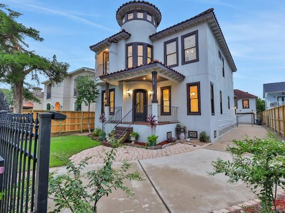 1408 W 23rd St, Houston, TX 77008 - mediterranean / spanish-style house featuring covered porch, stucco siding, fence, and a tile roof
