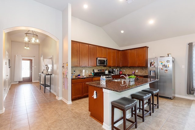 kitchen with appliances with stainless steel finishes, arched walkways, a sink, light tile patterned flooring, and recessed lighting