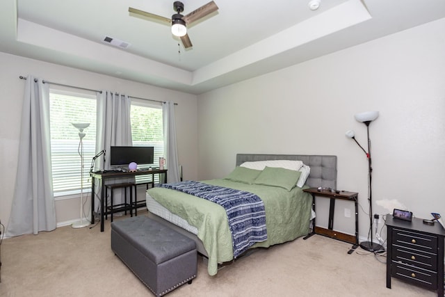 carpeted bedroom featuring a raised ceiling, baseboards, a desk, and ceiling fan