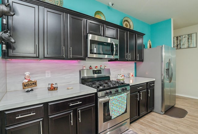 21003 Iris Holly St, Katy, TX 77449 - kitchen with dark cabinets, light wood-style floors, light countertops, and appliances with stainless steel finishes