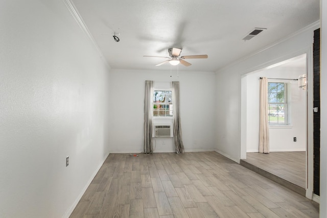 empty room featuring visible vents, a ceiling fan, ornamental molding, and light wood-style floors
