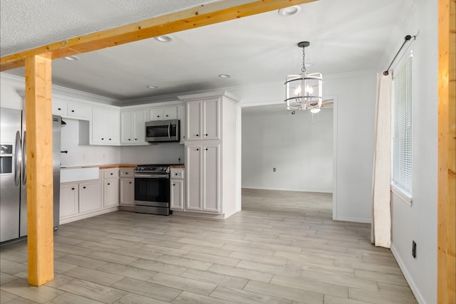 kitchen featuring a chandelier, stainless steel appliances, light wood-style floors, crown molding, and white cabinets
