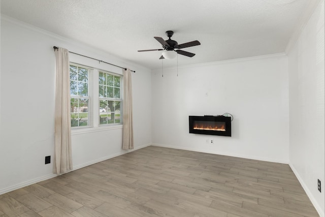 unfurnished living room with wood finished floors, ceiling fan, crown molding, and a glass covered fireplace